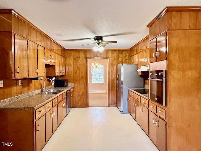 1007 Driftwood Dr, Siler City, NC 27344 - kitchen with black appliances, ceiling fan, brown cabinets, wood walls, and under cabinet range hood