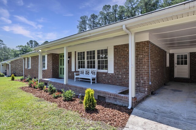 3009 Wellington Dr, Rocky Mount, NC 27803 - view of side of home featuring covered porch, brick siding, a carport, and driveway