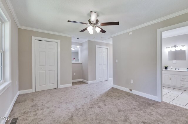 3009 Wellington Dr, Rocky Mount, NC 27803 - unfurnished bedroom featuring light colored carpet, ornamental molding, multiple closets, ensuite bathroom, and baseboards