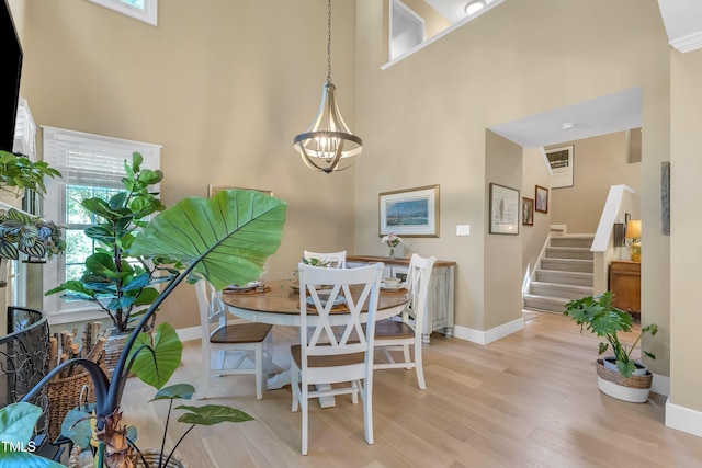 115 E Seve Ct, Morrisville, NC 27560 - dining space with a towering ceiling, light wood-style floors, stairs, baseboards, and a chandelier