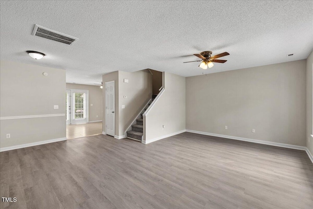 2228 Walnut Ridge Ct, Raleigh, NC 27610 - unfurnished living room with ceiling fan, wood finished floors, a textured ceiling, stairway, and baseboards