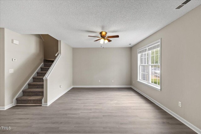 2228 Walnut Ridge Ct, Raleigh, NC 27610 - unfurnished living room with wood finished floors, a ceiling fan, a textured ceiling, stairs, and baseboards
