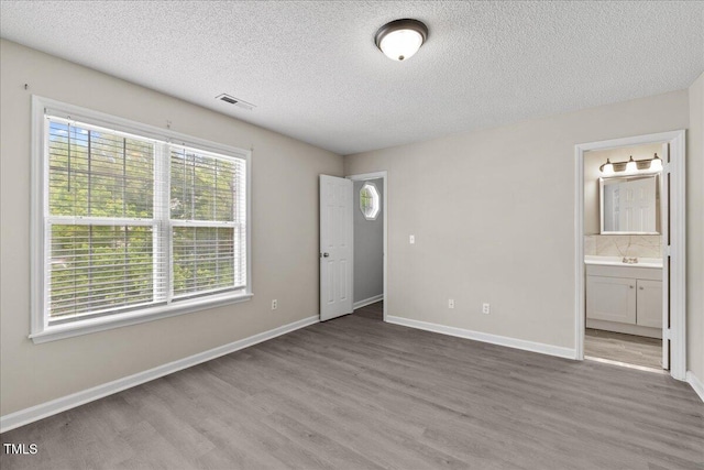 2228 Walnut Ridge Ct, Raleigh, NC 27610 - unfurnished bedroom featuring wood finished floors, a textured ceiling, baseboards, and ensuite bath