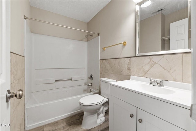 2228 Walnut Ridge Ct, Raleigh, NC 27610 - full bathroom with a textured ceiling, washtub / shower combination, vanity, toilet, and tile walls