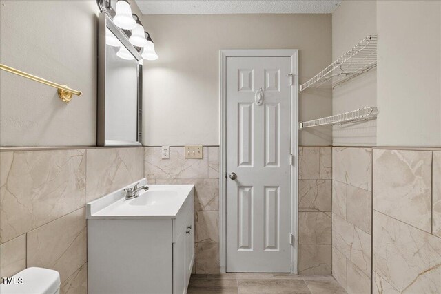 2228 Walnut Ridge Ct, Raleigh, NC 27610 - bathroom featuring tile walls, vanity, wainscoting, and toilet