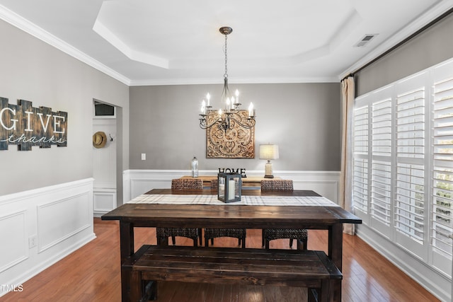 107 Trackimire Ln, Apex, NC 27539 - dining room featuring a tray ceiling, a chandelier, wood-type flooring, a wainscoted wall, and ornamental molding