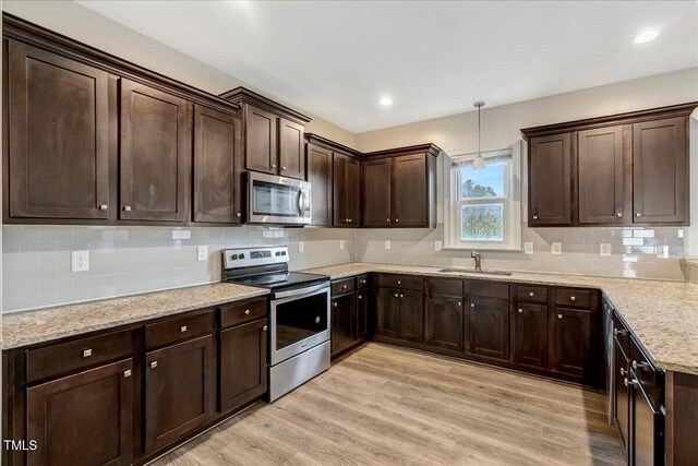 131 Hawick Ct, Zebulon, NC 27597 - kitchen with stainless steel appliances, dark brown cabinets, backsplash, and light wood finished floors