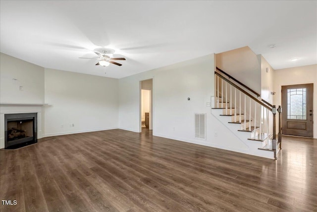 131 Hawick Ct, Zebulon, NC 27597 - unfurnished living room with dark wood-type flooring, a ceiling fan, stairway, and a fireplace with flush hearth