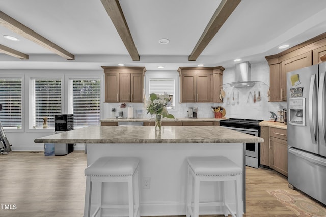 1118 Oakridge Duncan Rd, Fuquay Varina, NC 27526 - kitchen with appliances with stainless steel finishes, wall chimney exhaust hood, a kitchen bar, light wood-style floors, and decorative backsplash