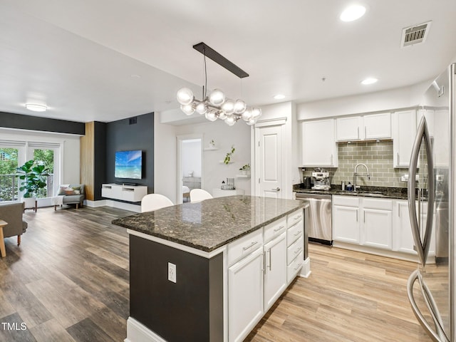 222 Glenwood Ave Unit 213, Raleigh, NC 27603 - kitchen featuring appliances with stainless steel finishes, decorative backsplash, white cabinetry, light wood-style floors, and dark stone counters