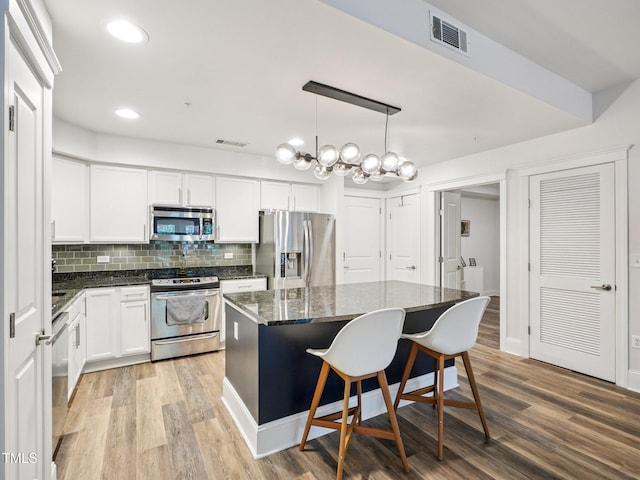 222 Glenwood Ave Unit 213, Raleigh, NC 27603 - kitchen with stainless steel appliances, a kitchen island, tasteful backsplash, dark stone counters, and light wood-style flooring