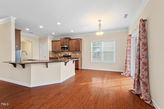 210 Strolling Way, Durham, NC 27707 - kitchen featuring stainless steel appliances, a breakfast bar area, a sink, ornamental molding, and wood finished floors