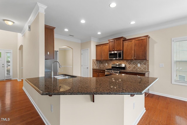 210 Strolling Way, Durham, NC 27707 - kitchen with appliances with stainless steel finishes, a sink, arched walkways, a kitchen bar, and decorative backsplash