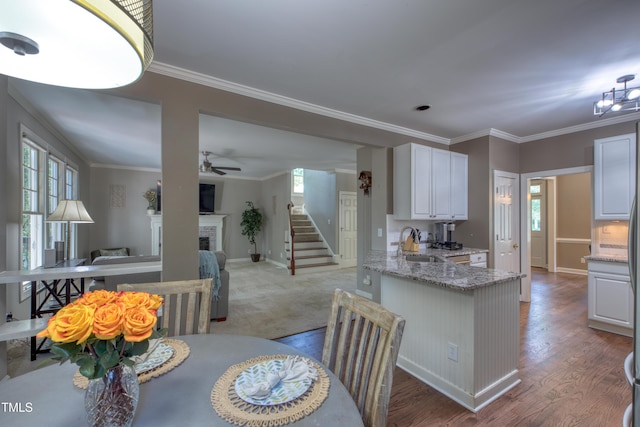 405 Widdington Ln, Cary, NC 27519 - dining area featuring a fireplace, healthy amount of natural light, wood finished floors, stairs, and crown molding