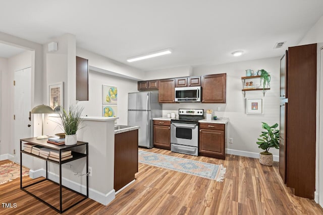 106 Choptank Ct Unit B-2, Cary, NC 27513 - kitchen with stainless steel appliances, light countertops, baseboards, light wood-type flooring, and a peninsula