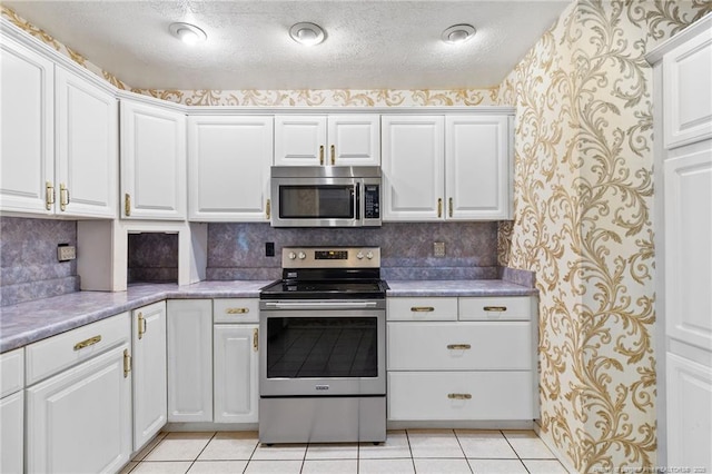 741 Ashboro St, Fayetteville, NC 28311 - kitchen featuring appliances with stainless steel finishes, wallpapered walls, light tile patterned floors, white cabinets, and light countertops