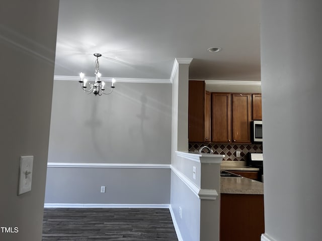 1527 Haywards Heath Ln, Apex, NC 27502 - kitchen with stainless steel microwave, backsplash, a chandelier, ornamental molding, and dark wood-type flooring