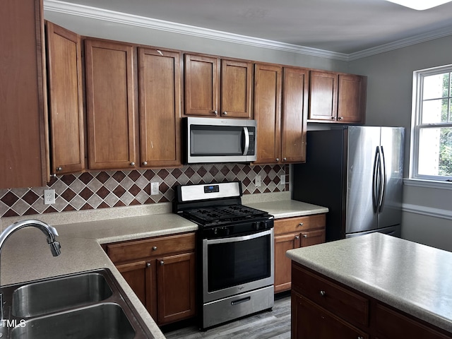 1527 Haywards Heath Ln, Apex, NC 27502 - kitchen with stainless steel appliances, a sink, brown cabinetry, and crown molding