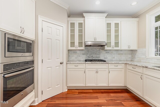 7604 Copper Creek Ct, Wake Forest, NC 27587 - kitchen featuring appliances with stainless steel finishes, under cabinet range hood, white cabinetry, ornamental molding, and light wood finished floors