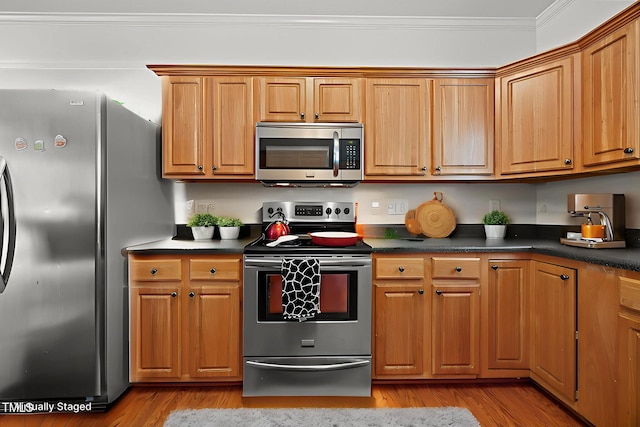 106 Oak Rd, Butner, NC 27509 - kitchen featuring stainless steel appliances, dark countertops, ornamental molding, light wood-style floors, and brown cabinetry
