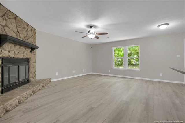 6263 Stoney Point Loop, Fayetteville, NC 28306 - unfurnished living room featuring ceiling fan, light wood-type flooring, baseboards, and a stone fireplace