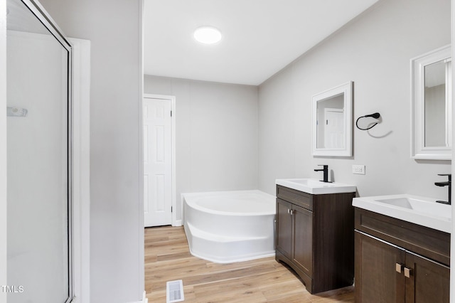 752 Dundee Cir, Raeford, NC 28376 - full bathroom featuring wood finished floors, a garden tub, two vanities, and a stall shower