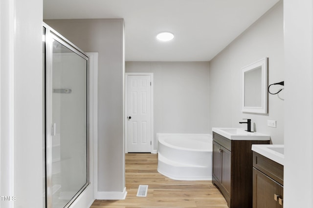 752 Dundee Cir, Raeford, NC 28376 - bathroom featuring a shower stall, two vanities, a garden tub, and wood finished floors