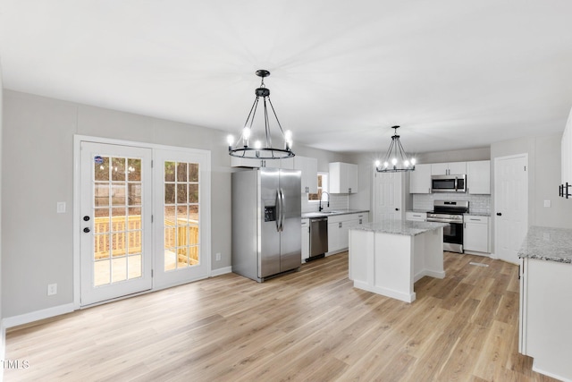752 Dundee Cir, Raeford, NC 28376 - kitchen with stainless steel appliances, a chandelier, light wood-type flooring, decorative backsplash, and a center island