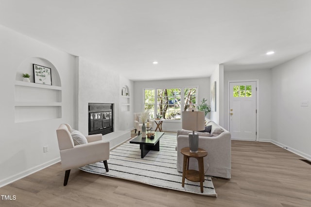 216 Burkwood Ln, Raleigh, NC 27609 - living area with built in features, baseboards, a glass covered fireplace, wood finished floors, and recessed lighting