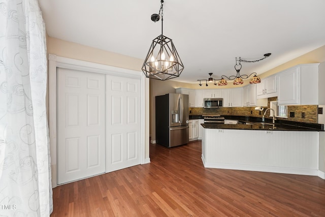 304 Cayman Ave, Holly Springs, NC 27540 - kitchen with stainless steel appliances, dark countertops, a peninsula, and tasteful backsplash