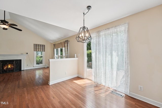 304 Cayman Ave, Holly Springs, NC 27540 - unfurnished dining area with wood finished floors, baseboards, a ceiling fan, a warm lit fireplace, and vaulted ceiling