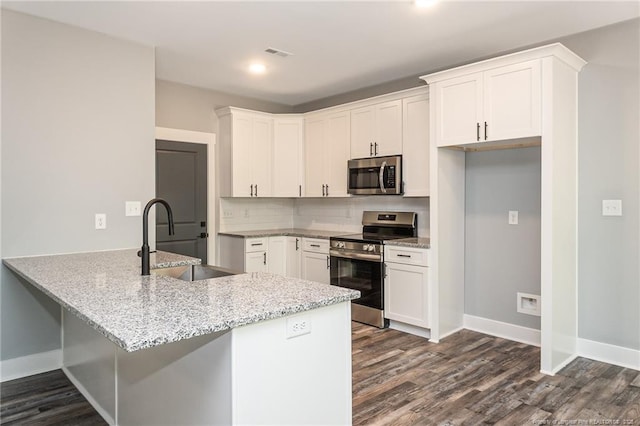 3029 Candlelight Dr, Fayetteville, NC 28311 - kitchen with stainless steel appliances, a sink, a peninsula, dark wood-type flooring, and light stone countertops