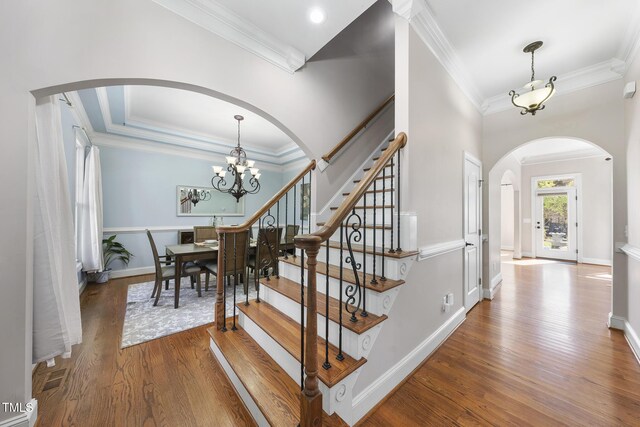 1006 Henny Pl, Raleigh, NC 27614 - staircase featuring arched walkways, ornamental molding, wood finished floors, a chandelier, and baseboards