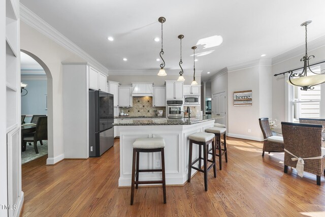 1006 Henny Pl, Raleigh, NC 27614 - kitchen featuring appliances with stainless steel finishes, custom range hood, arched walkways, decorative backsplash, and crown molding