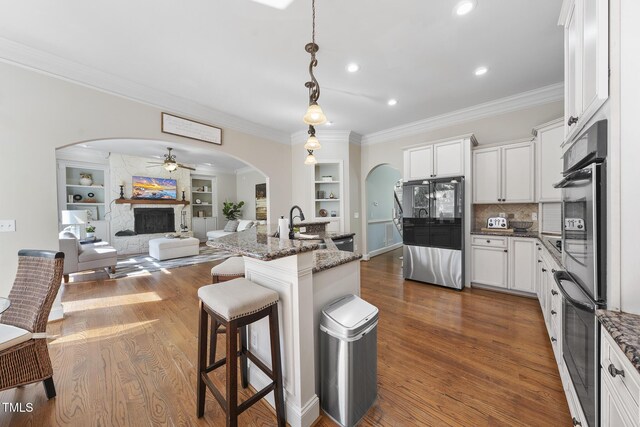 1006 Henny Pl, Raleigh, NC 27614 - kitchen with arched walkways, refrigerator, ornamental molding, a stone fireplace, and ceiling fan