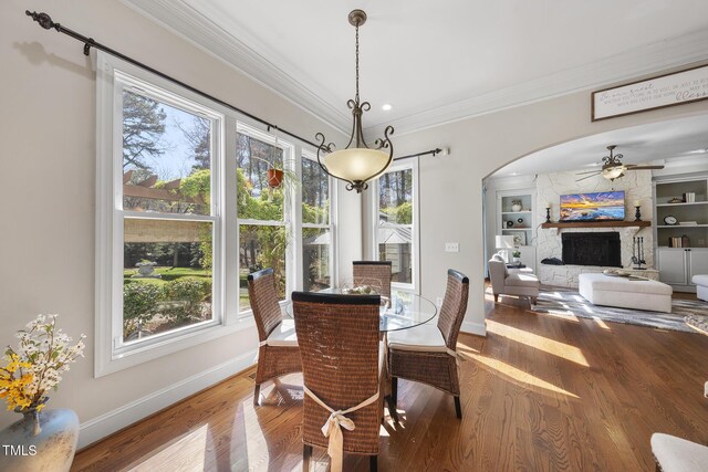 1006 Henny Pl, Raleigh, NC 27614 - dining room featuring crown molding, wood finished floors, arched walkways, baseboards, and a fireplace