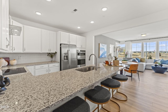 138 N White St # 100, Wake Forest, NC 27587 - kitchen with stainless steel appliances, a sink, light stone countertops, a breakfast bar area, and open floor plan