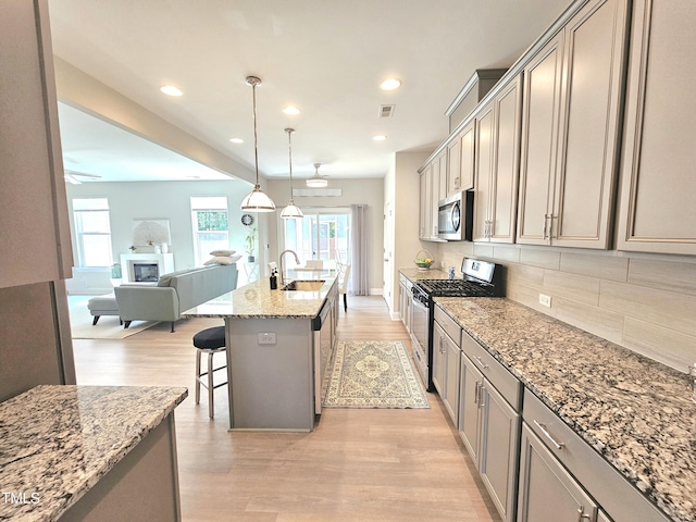 1412 Queen Trigger Dr, Fuquay Varina, NC 27526 - kitchen featuring appliances with stainless steel finishes, a sink, backsplash, a kitchen bar, and open floor plan