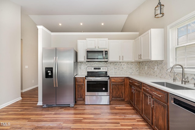 5437 Advantis Dr, Raleigh, NC 27610 - kitchen with appliances with stainless steel finishes, a sink, light wood-style floors, decorative backsplash, and vaulted ceiling