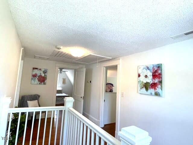 11609 US-401, Fuquay Varina, NC 27526 - hallway featuring an upstairs landing, a textured ceiling, and attic access