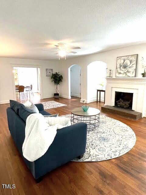 11609 US-401, Fuquay Varina, NC 27526 - living area featuring arched walkways, ceiling fan, a fireplace with raised hearth, baseboards, and wood finished floors
