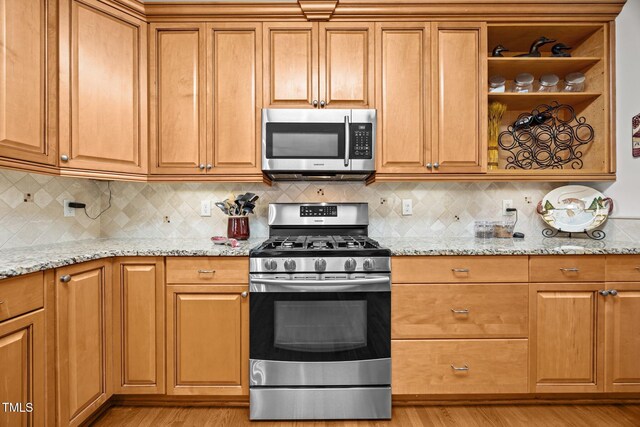 1412 Kings Lassiter Way, Raleigh, NC 27614 - kitchen with stainless steel appliances, light wood finished floors, light stone countertops, and brown cabinetry
