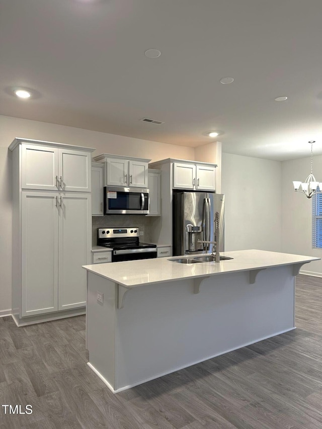 391 Curling Crk Dr, Clayton, NC 27527 - kitchen featuring stainless steel appliances, dark wood-type flooring, a spacious island, a breakfast bar area, and light countertops