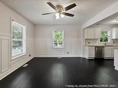 3914 Coventry Rd, Fayetteville, NC 28304 - unfurnished living room with a decorative wall, a ceiling fan, healthy amount of natural light, wainscoting, and dark wood-style floors