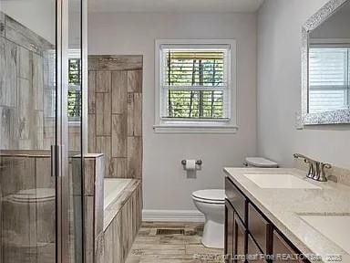 3914 Coventry Rd, Fayetteville, NC 28304 - full bath featuring toilet, a garden tub, double vanity, a tile shower, and baseboards
