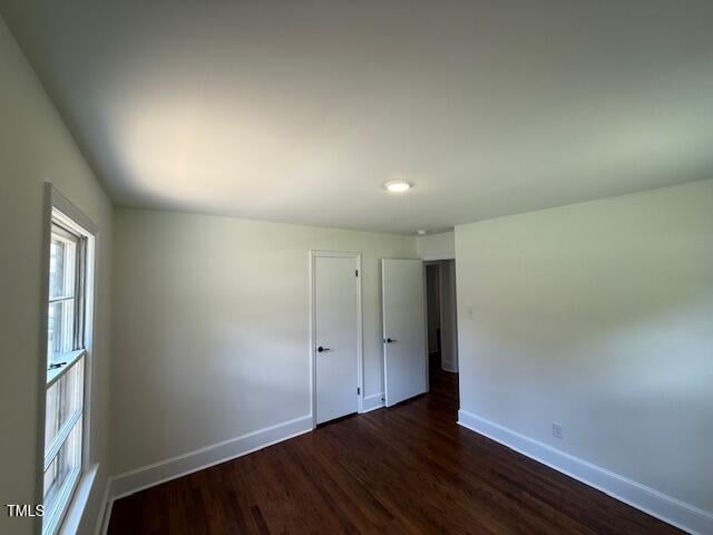 902 Roanoke Ave, Henderson, NC 27536 - unfurnished bedroom with baseboards and dark wood-style flooring
