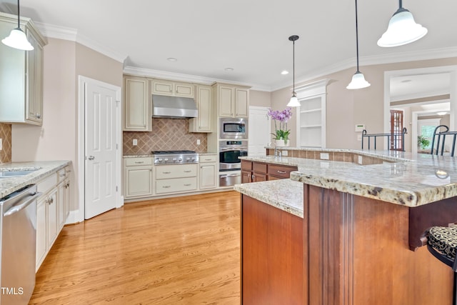 3004 Krogen Ct, Creedmoor, NC 27522 - kitchen with under cabinet range hood, stainless steel appliances, cream cabinetry, a warming drawer, and light wood-type flooring