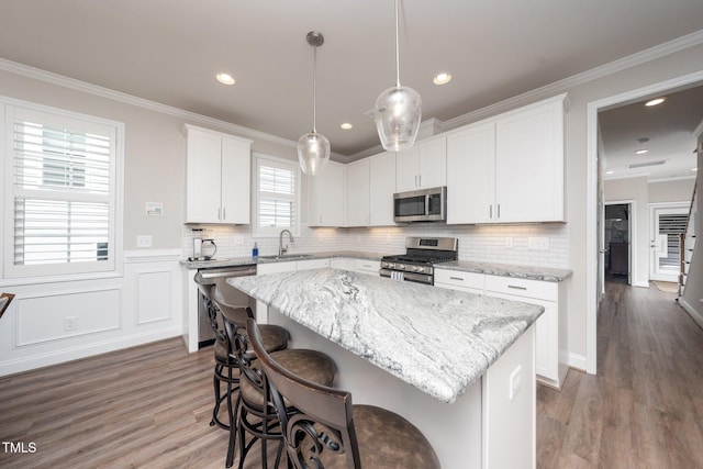 1705 Main Divide Dr, Wake Forest, NC 27587 - kitchen with appliances with stainless steel finishes, a sink, a breakfast bar, a center island, and wood finished floors