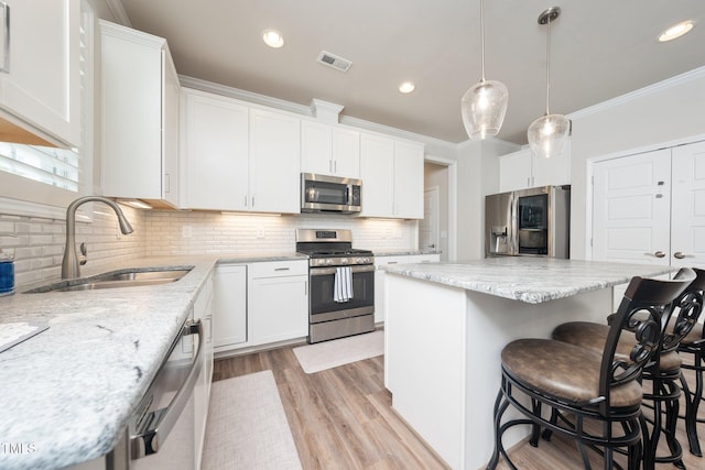 1705 Main Divide Dr, Wake Forest, NC 27587 - kitchen featuring appliances with stainless steel finishes, a sink, a breakfast bar area, backsplash, and a center island