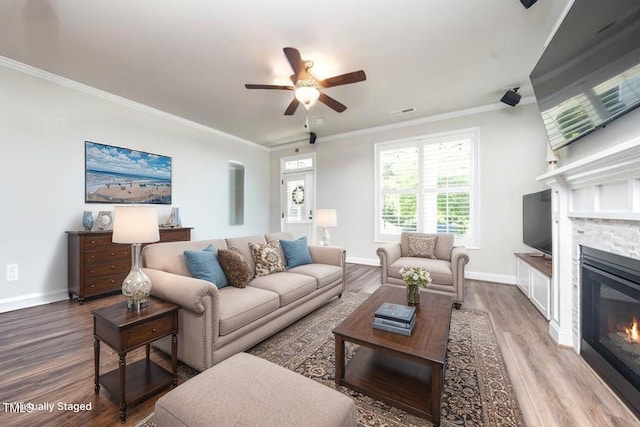 1705 Main Divide Dr, Wake Forest, NC 27587 - living area featuring a stone fireplace, crown molding, wood finished floors, a ceiling fan, and baseboards